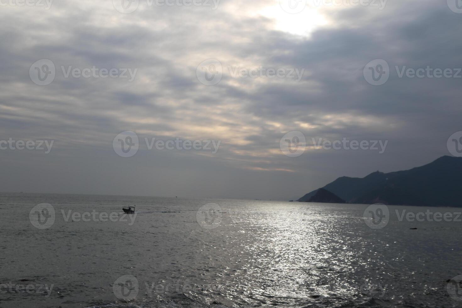 The sea, the sky is cloudy, and there is some sun shining through the clouds on part of it photo