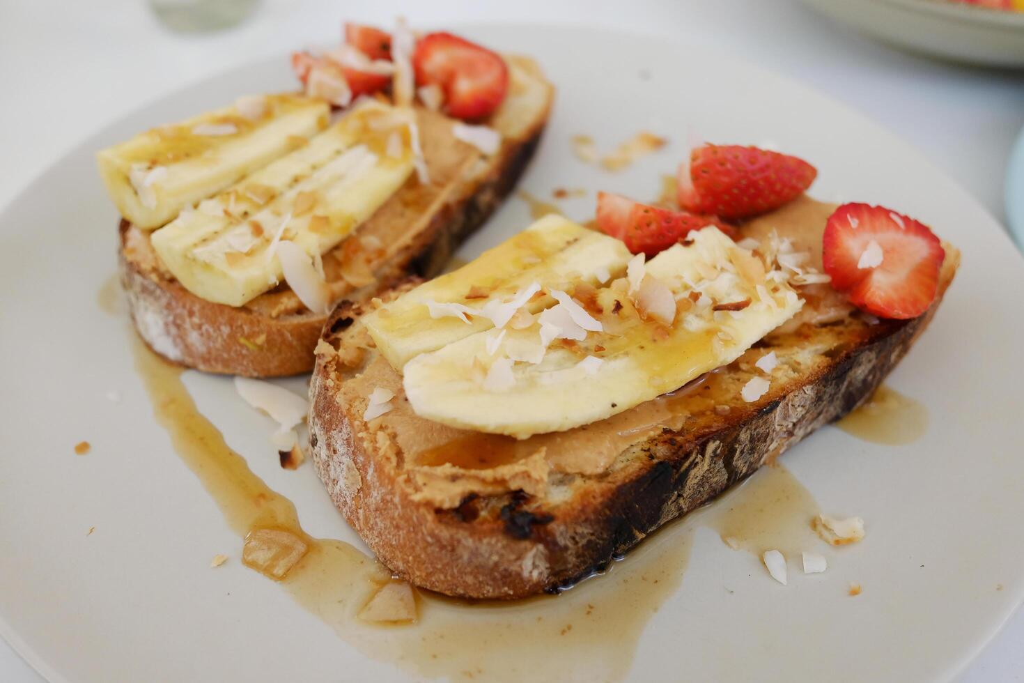 Homemade fresh strawberries with banana and cream cheese on wheat bread with honey and almond peanut topping. French almond toast delicious breakfast or dessert photo