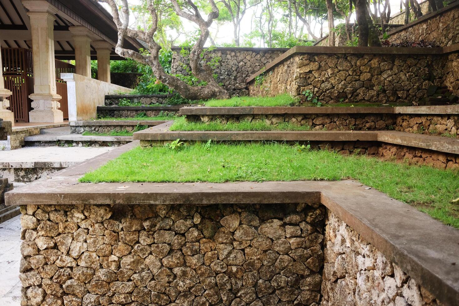 Fresh green grass grows on concrete steps in tropical garden courtyard decorated in ancient Hindu temple in Bali, Indonesia photo