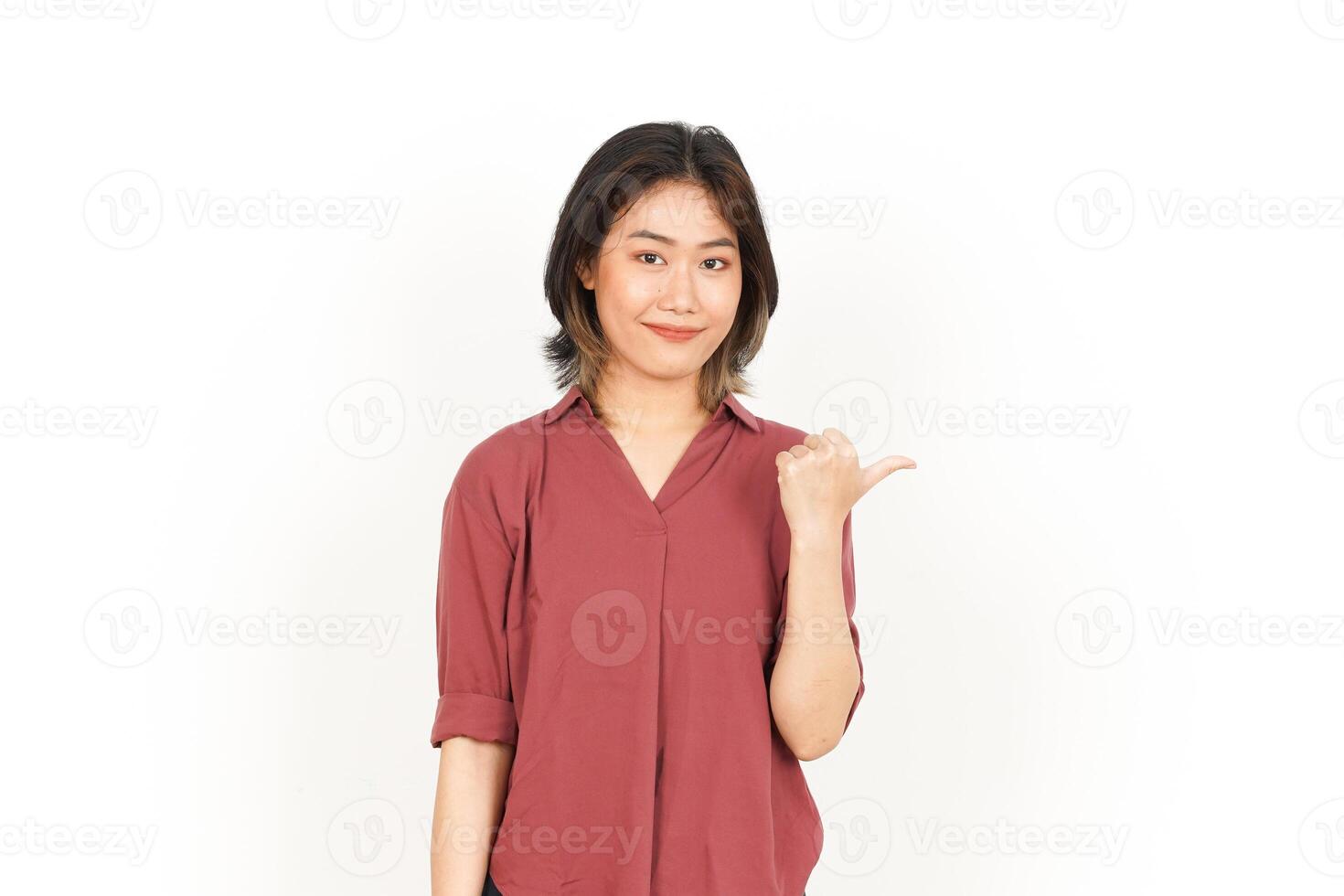 Showing and Pointing Product With Thumb Of Beautiful Asian Woman Isolated On White Background photo