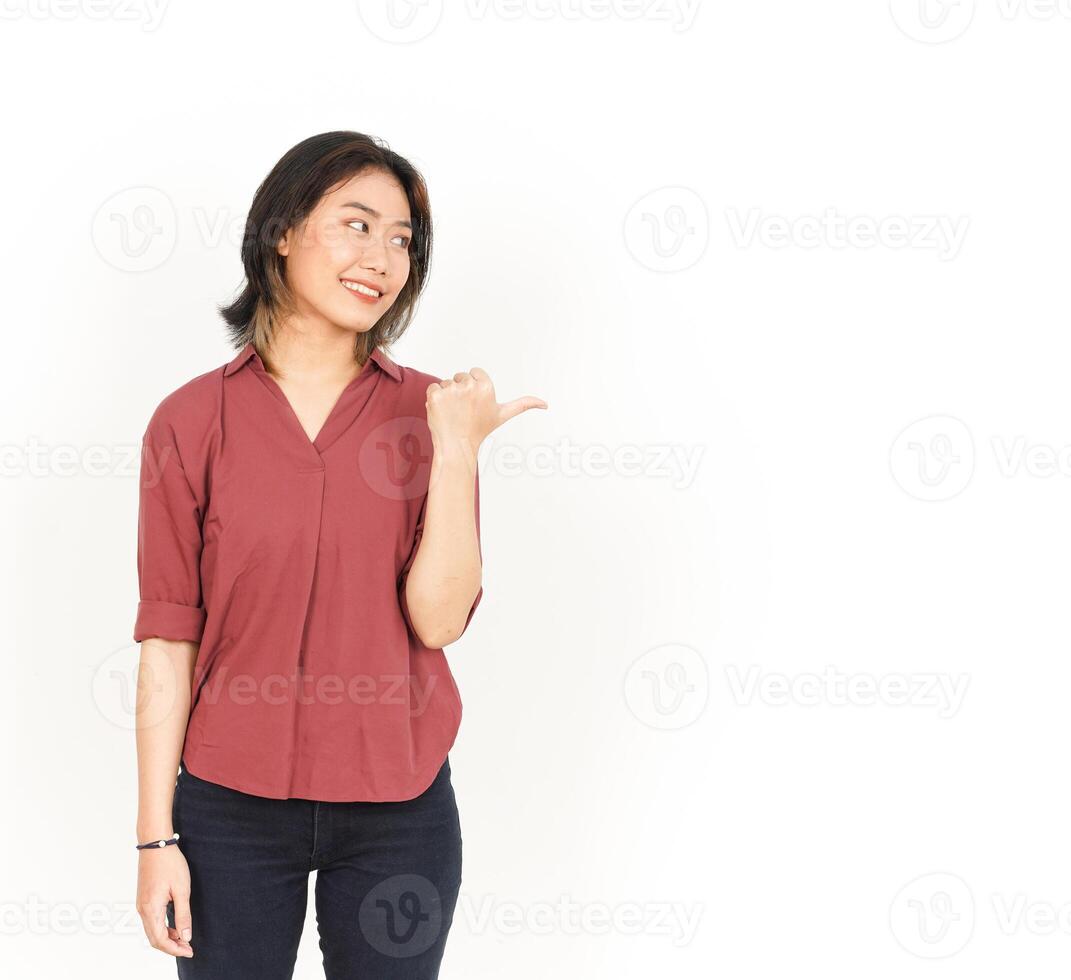 Showing and Pointing Product With Thumb Of Beautiful Asian Woman Isolated On White Background photo