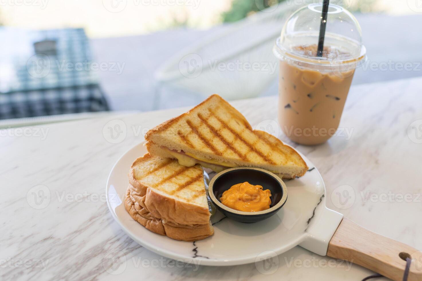 Ham cheese sandwich with custard sauce and ice coffee on marble photo