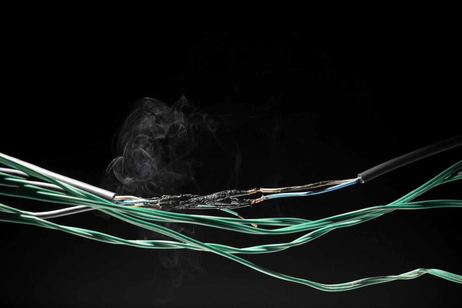 Smoke from electric shock Short-circuiting cables can cause sparks, explosions, excessive electrical consumption. Damaged equipment and substandard equipment on a dark black background photo