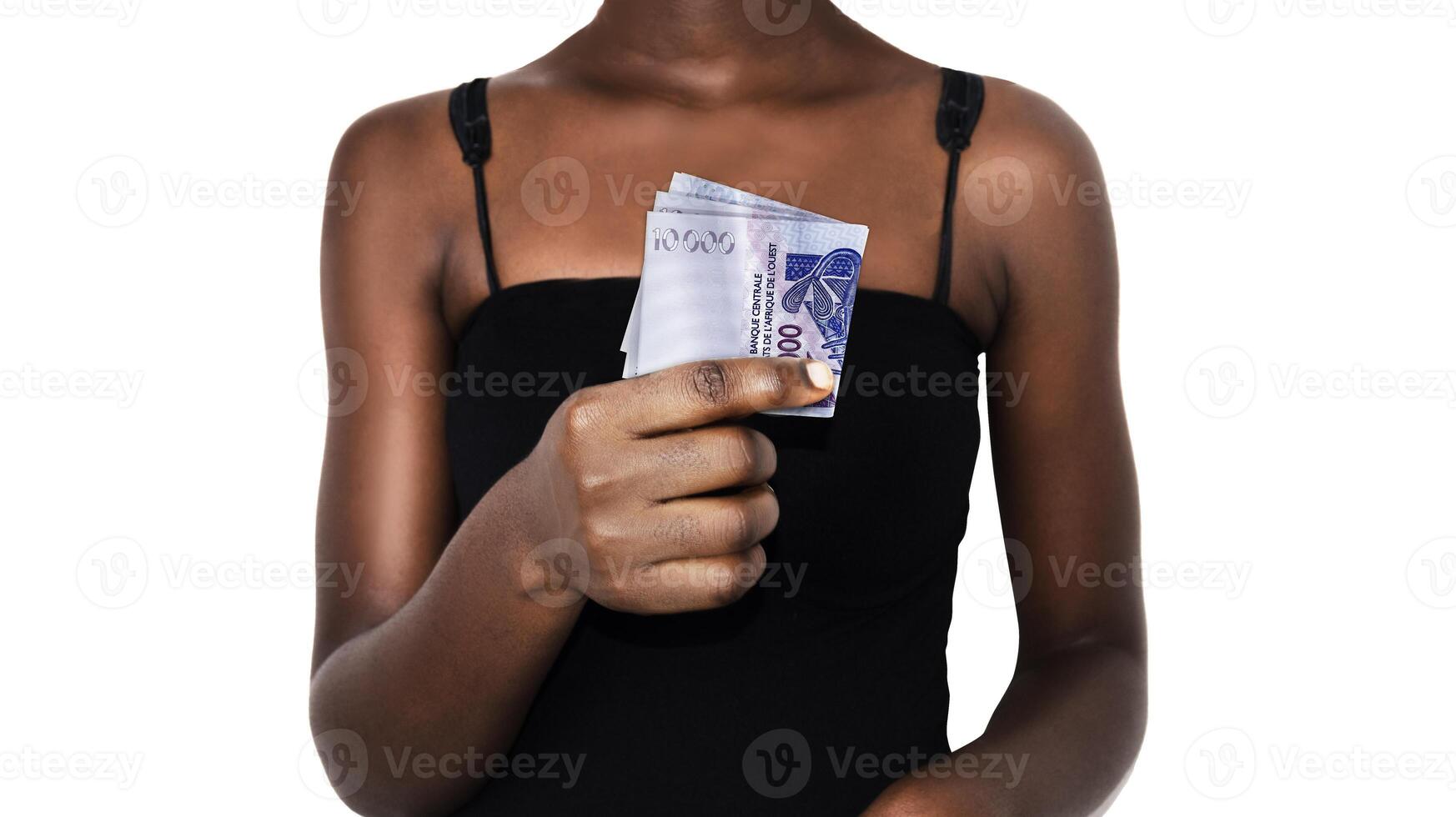 Black African lady woman female in Black tank top holding showing west CFA franc note to camera over white background, currency of west africa photo