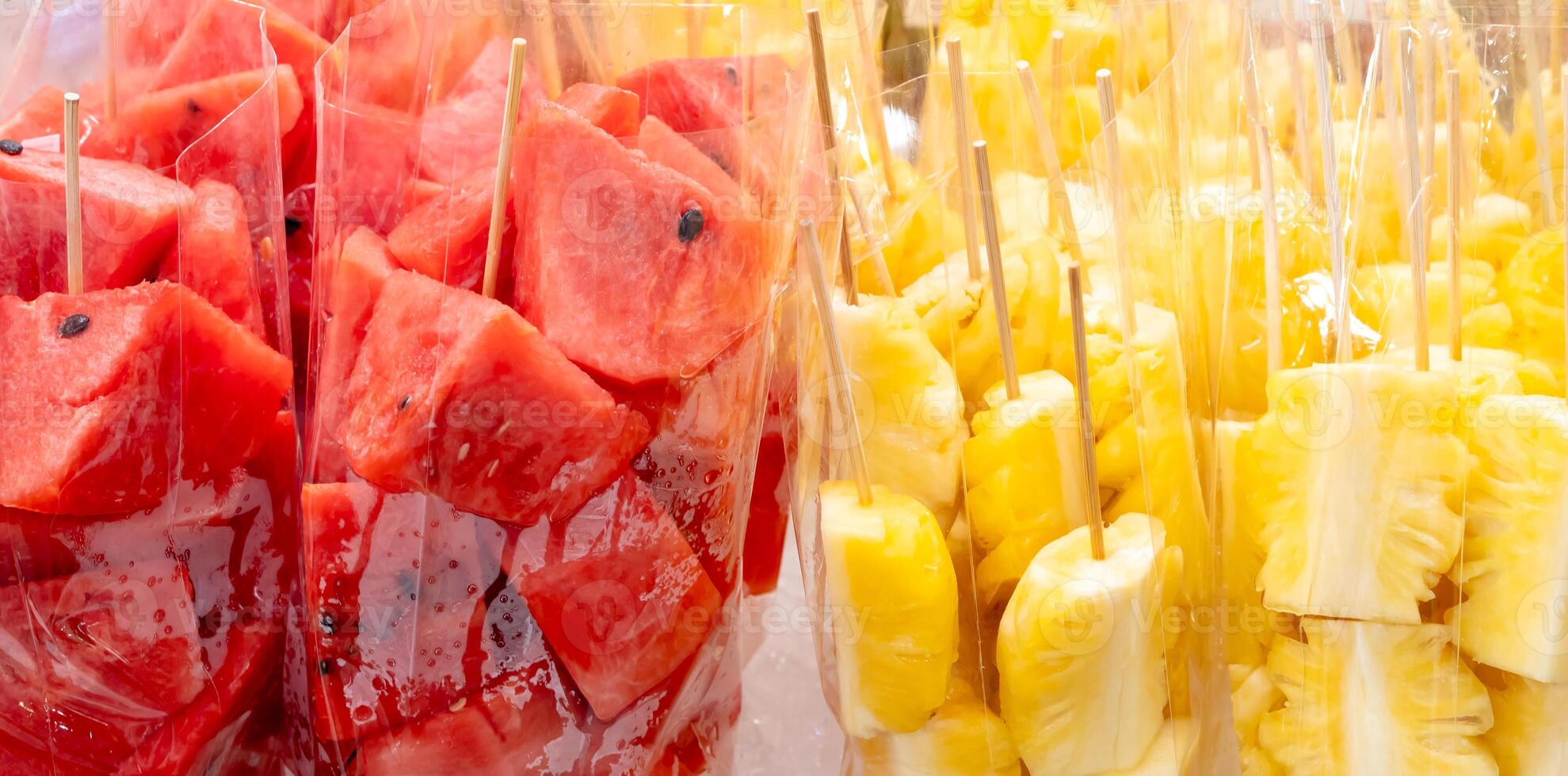 Full frame of red watermelon and yellow pineapple in pieces or slices in transparent plastic bag on sale at street food stall photo