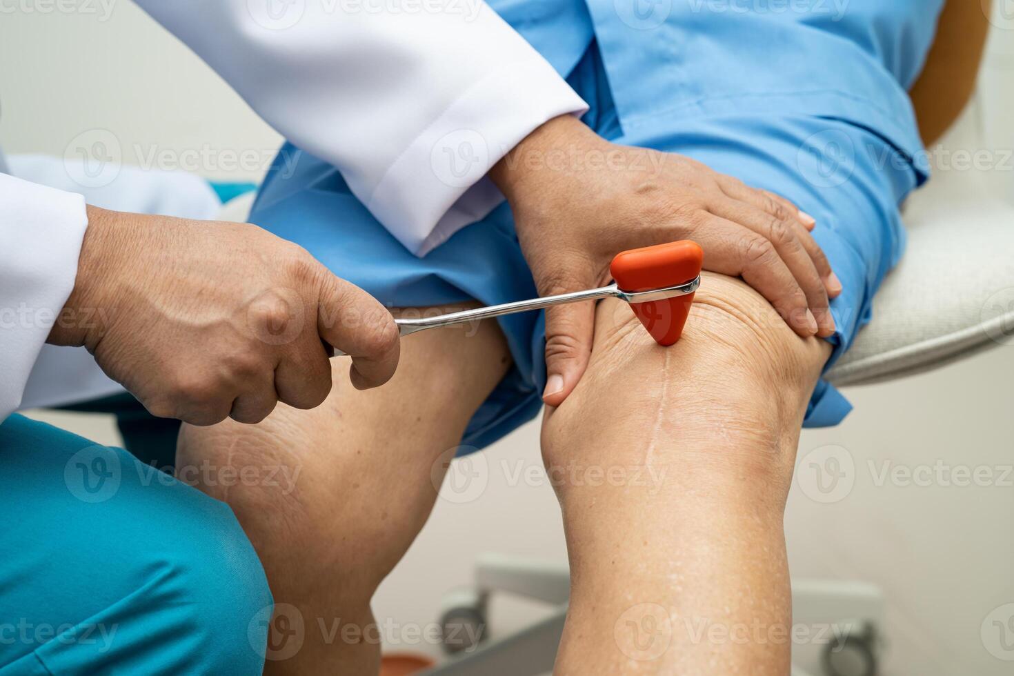 Asian doctor use hammer knock senior woman patient to check knee reflex, nerve and muscle in hospital. photo