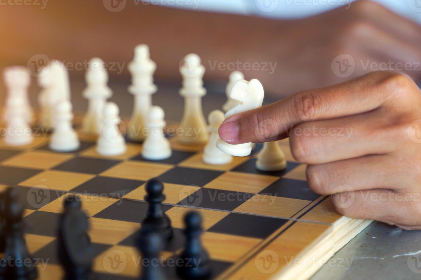 Close-up of a chess player's hand moving pieces on the board as planned to defeat the opponent. Soft and selective focus. photo