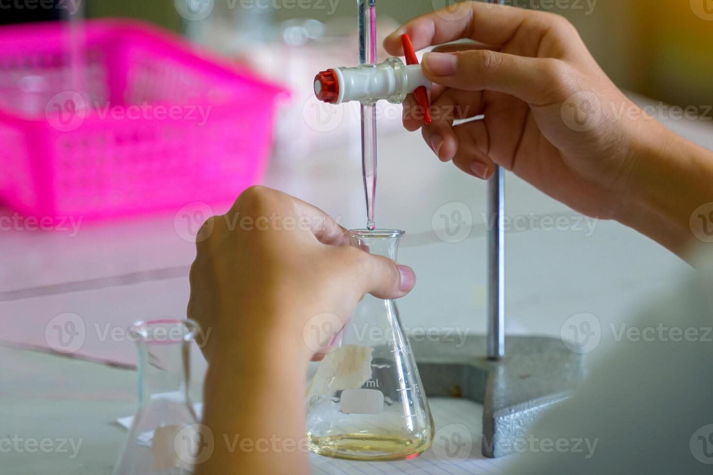 Close-up of a student performing an acid-base titration experiment. Concept of chemistry lab, science, experiment, skills, learning. photo