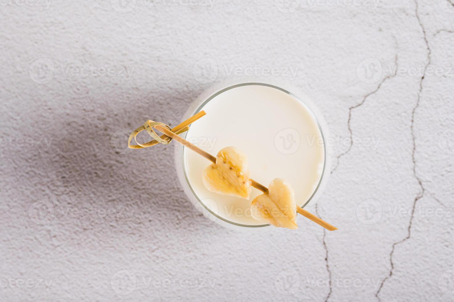 Close up of alternative lactose free banana milk in a glass on the table top view photo
