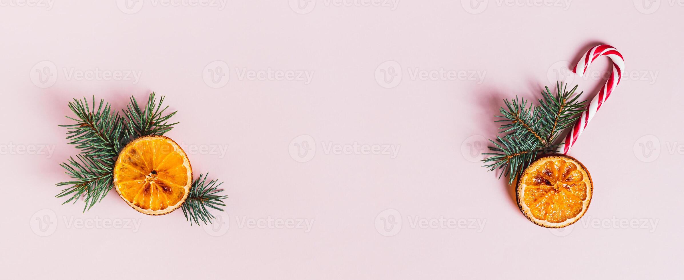 Christmas arrangement of fir branches, dried orange and candy cane on pink top view web banner photo