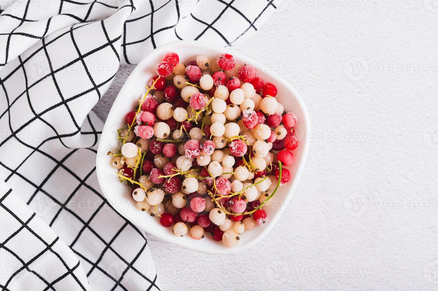 Close up of frozen red and white currants in bowl on table top view photo