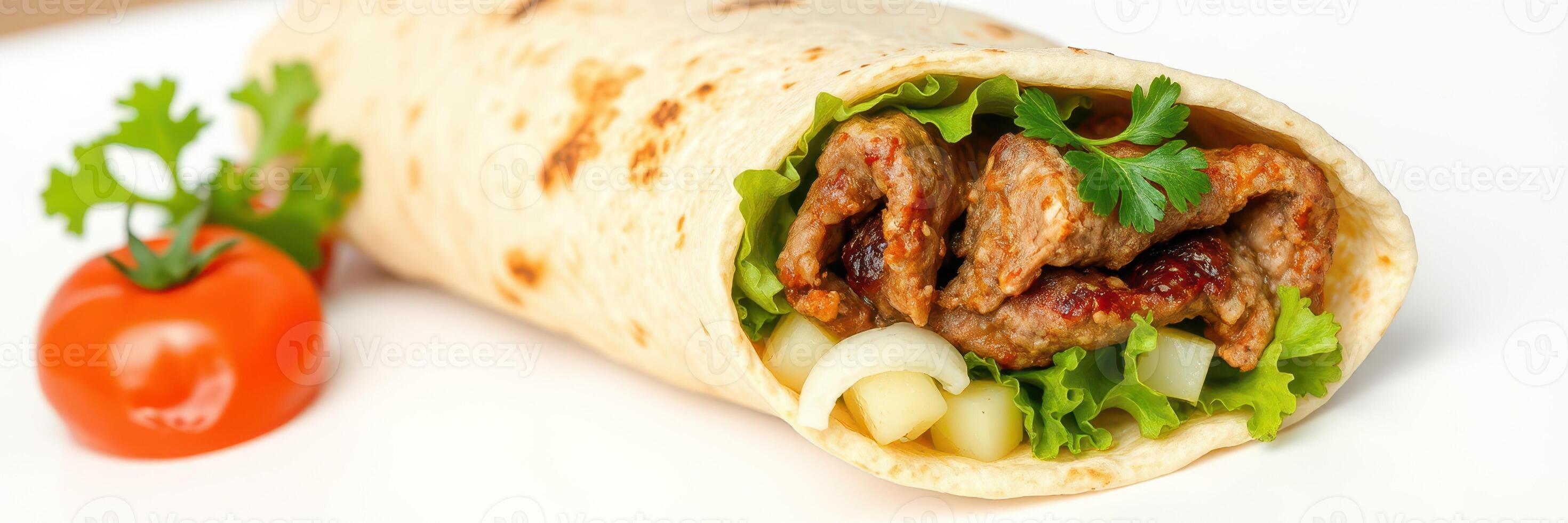 Savory wrap filled with grilled meat, fresh vegetables, and herbs served on a white plate photo