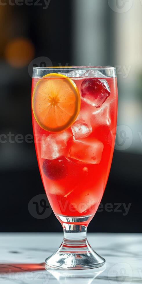 Refreshing red citrus drink served in a clear glass with ice and a slice of orange photo