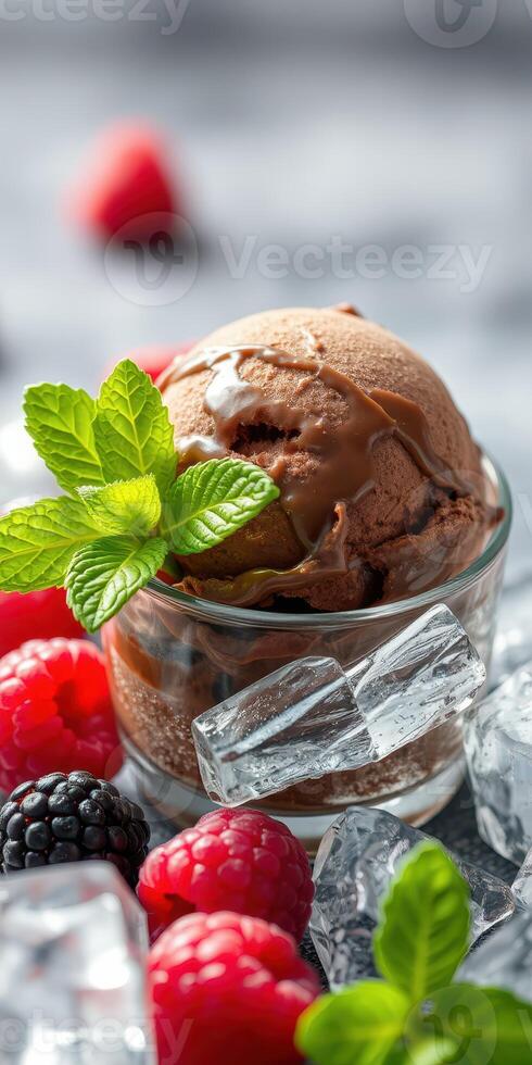 Chocolate ice cream served in a glass dish surrounded by fresh berries and ice cubes on a gray background photo