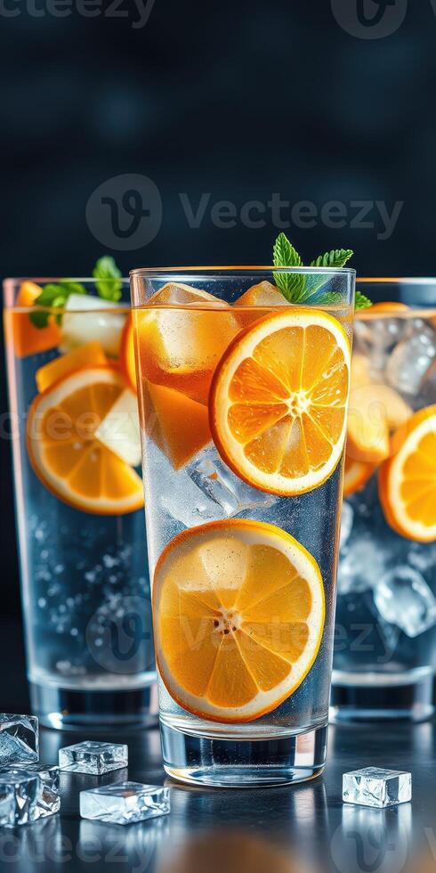 Refreshing citrus drinks filled with ice and garnished with mint leaves served in tall glasses photo