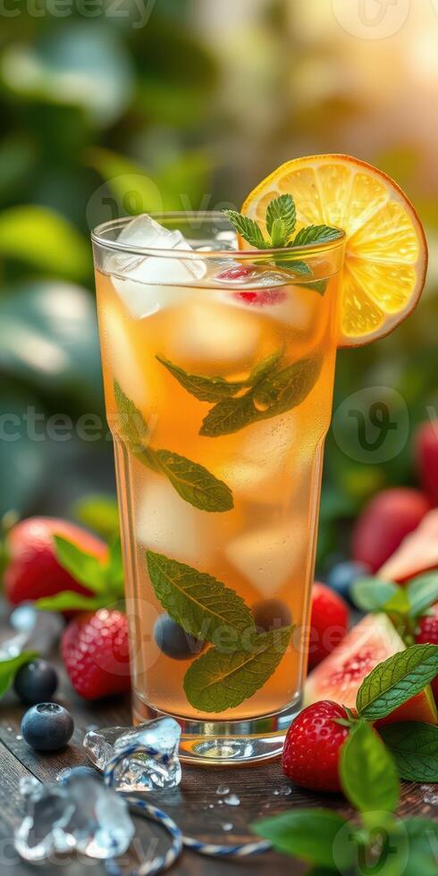 Refreshing iced tea with lemon and mint garnished with berries on a wooden table in a garden setting photo