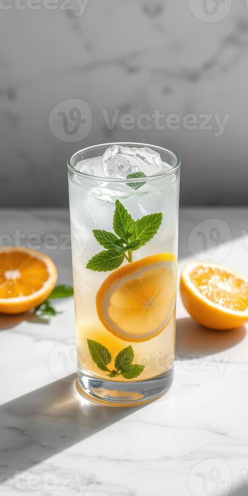 Refreshing lemon mint drink with ice in a tall glass on a marble surface photo