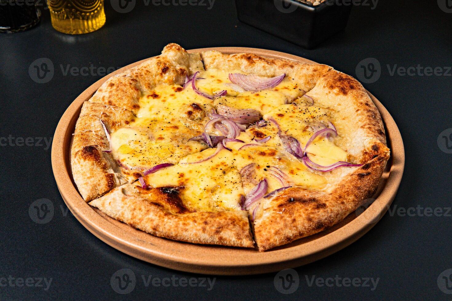 a pizza with onions and onions on it sits on a table. photo