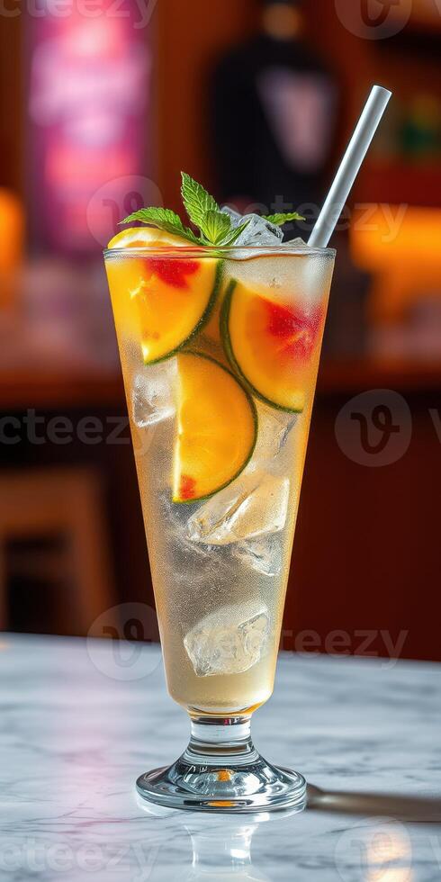 Refreshing fruit cocktail served in a tall glass filled with ice and garnished with mint and sliced peaches photo