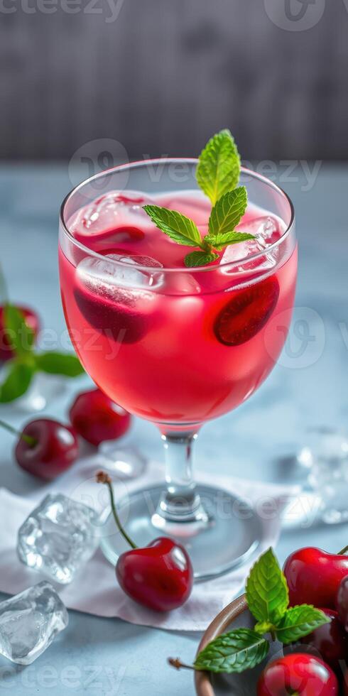 Refreshing cherry mint beverage with ice and cherries in a glass on a light blue background photo