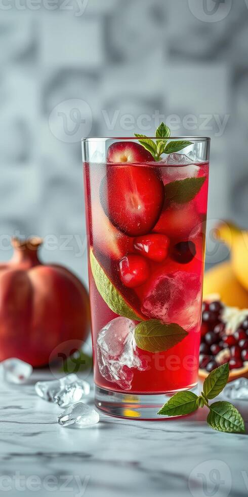 Refreshing summer beverage with fresh fruits and ice served in a tall glass on a marble countertop photo