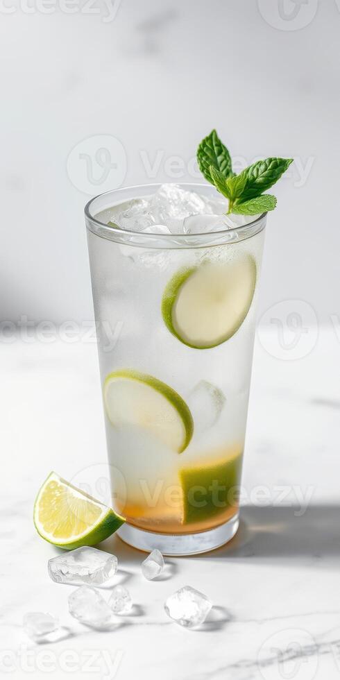Refreshing lime and mint cocktail served in a tall glass with ice on a marble countertop photo