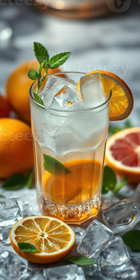 Refreshing citrus drink garnished with mint served in a clear glass with ice cubes alongside fresh oranges photo