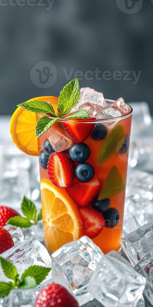 Refreshing summer beverage filled with fruits served cold on ice with mint garnish in a glass photo