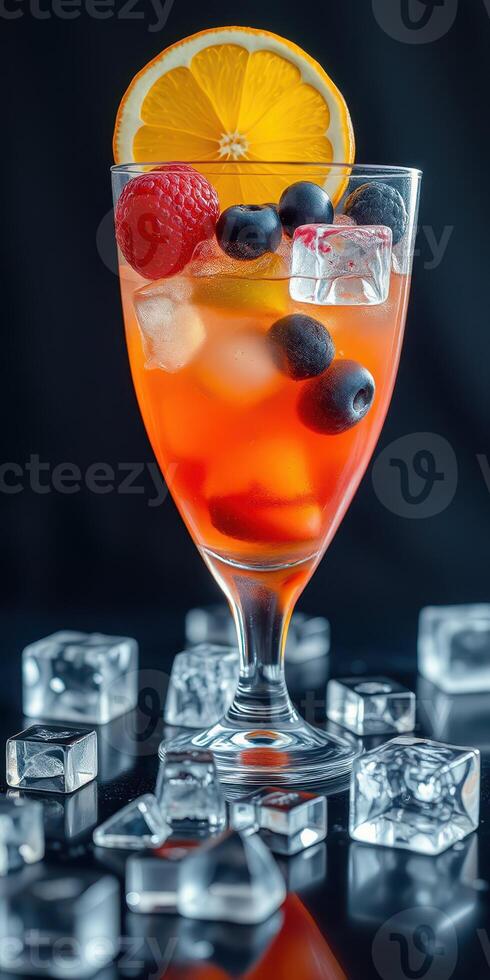 Refreshing fruit cocktail garnished with orange, raspberry, and blueberry on a dark background photo