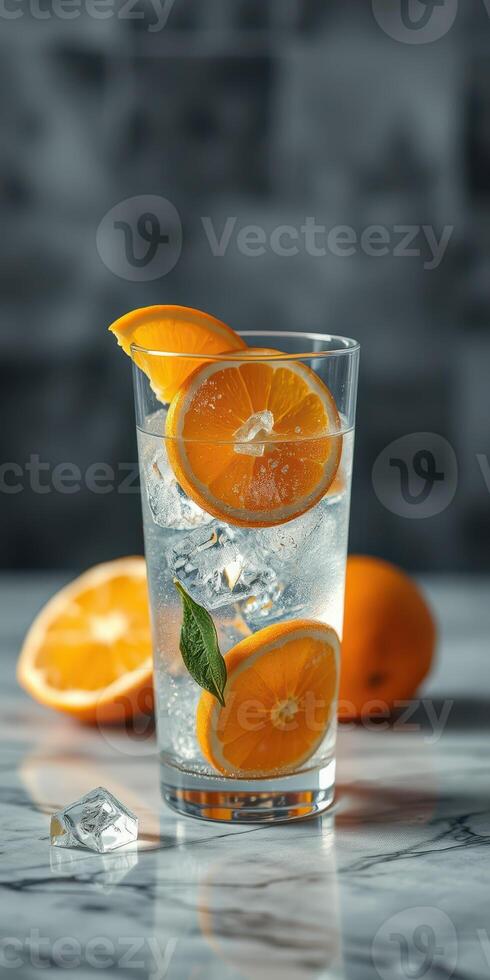Refreshing citrus drink with ice and orange slices displayed on a marble surface photo