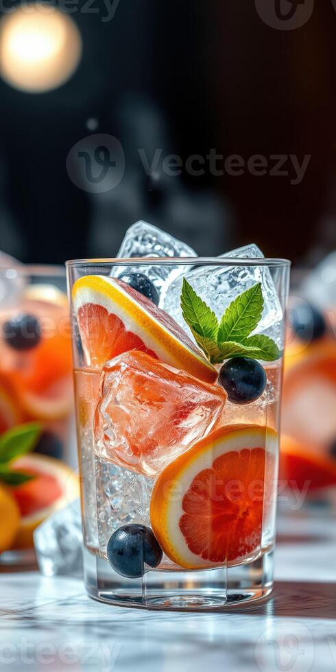 Refreshing fruit cocktail with ice and mint displayed in a clear glass on a marble surface photo