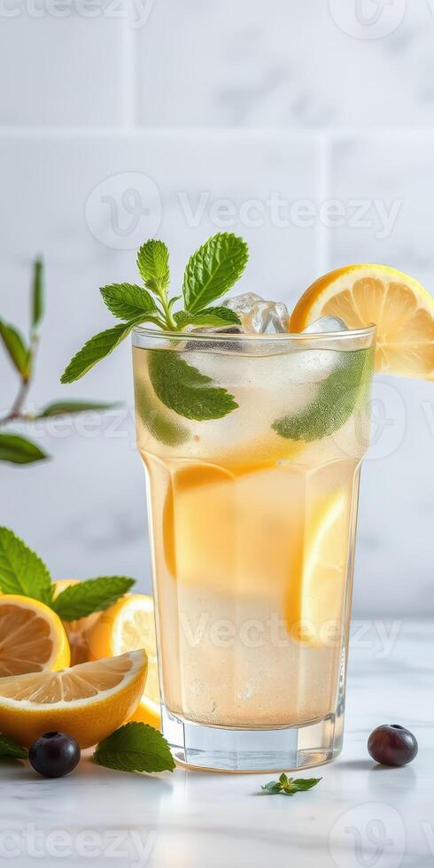 Refreshing citrus drink with mint and lemon served in a tall glass on a marble countertop photo