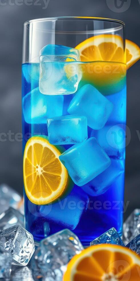 Refreshing blue citrus drink with ice and lemon slices in a tall glass on a dark background photo