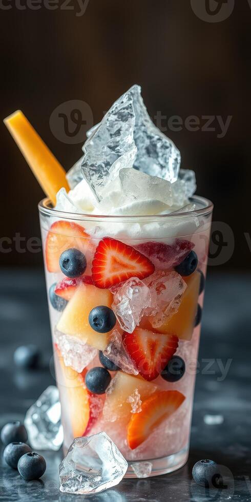 Refreshing fruit dessert served in a clear glass with colorful berries and ice on a dark surface photo