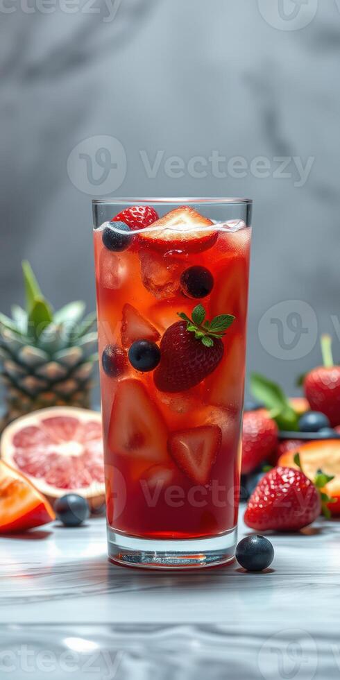 Refreshing summer drink with berries and citrus in a tall glass on a marble surface photo