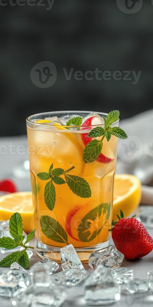Refreshing fruit cocktail with mint and ice served in a glass on a table with citrus fruit and strawberries photo