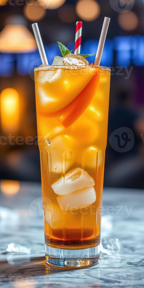 Refreshing beverage served in a tall glass with ice, fruit garnish, and straws at a vibrant bar in the evening photo