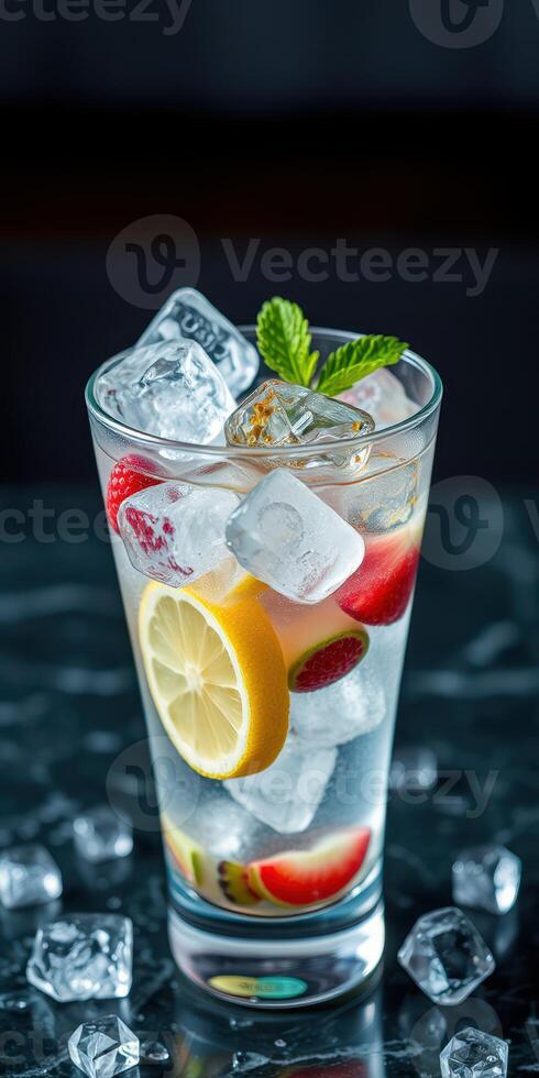 Refreshing summer drink with ice, citrus, and mint served in a glass on a dark tabletop photo