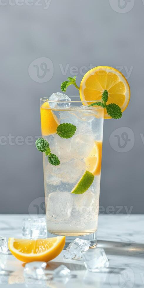 Refreshing lemon and mint drink served in a tall glass on a marble surface with ice and lemon slices photo