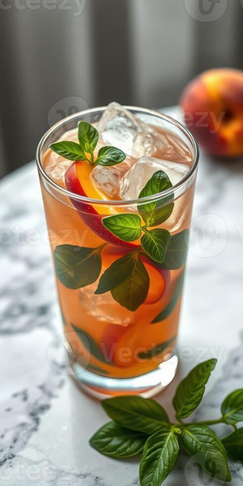Refreshing herbal peach beverage with ice and mint leaves on a marble surface photo