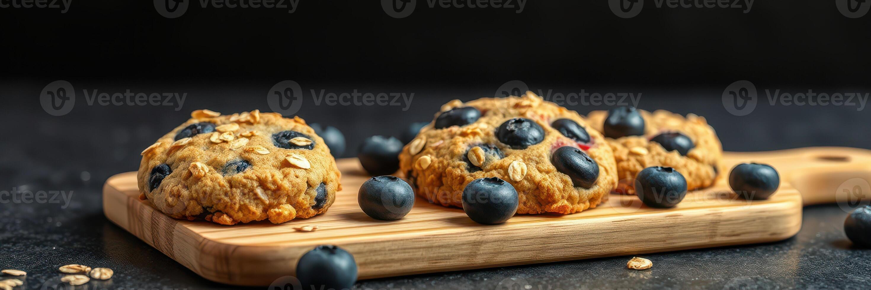 Delicious oat and blueberry cookies arranged on a wooden board with fresh blueberries beside them photo