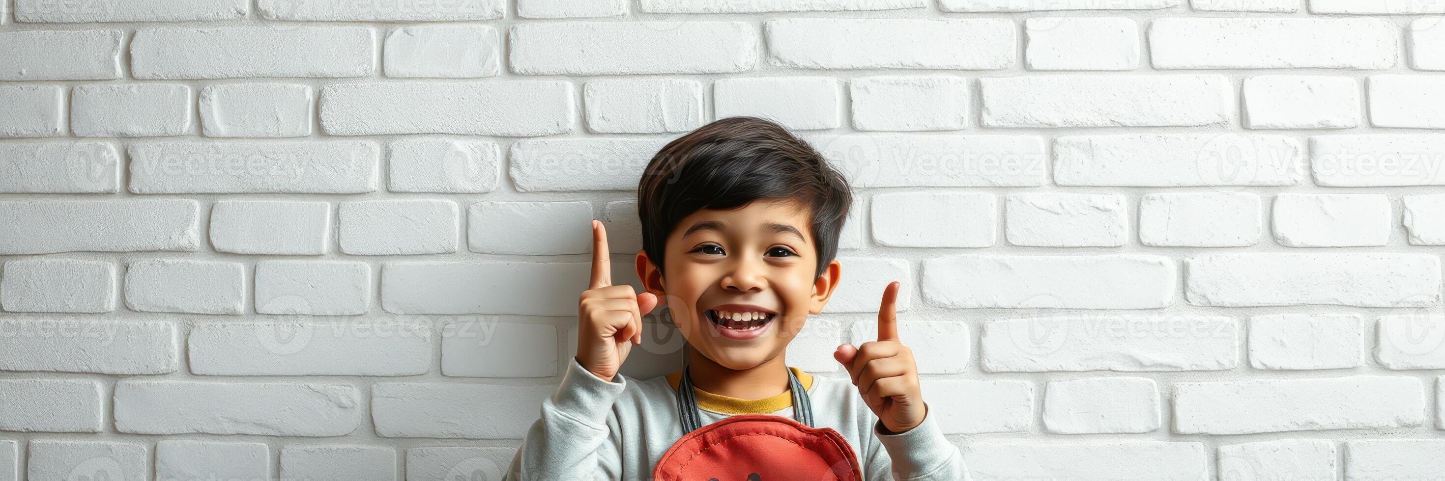 Happy child celebrating success with a big smile in front of a white brick wall photo