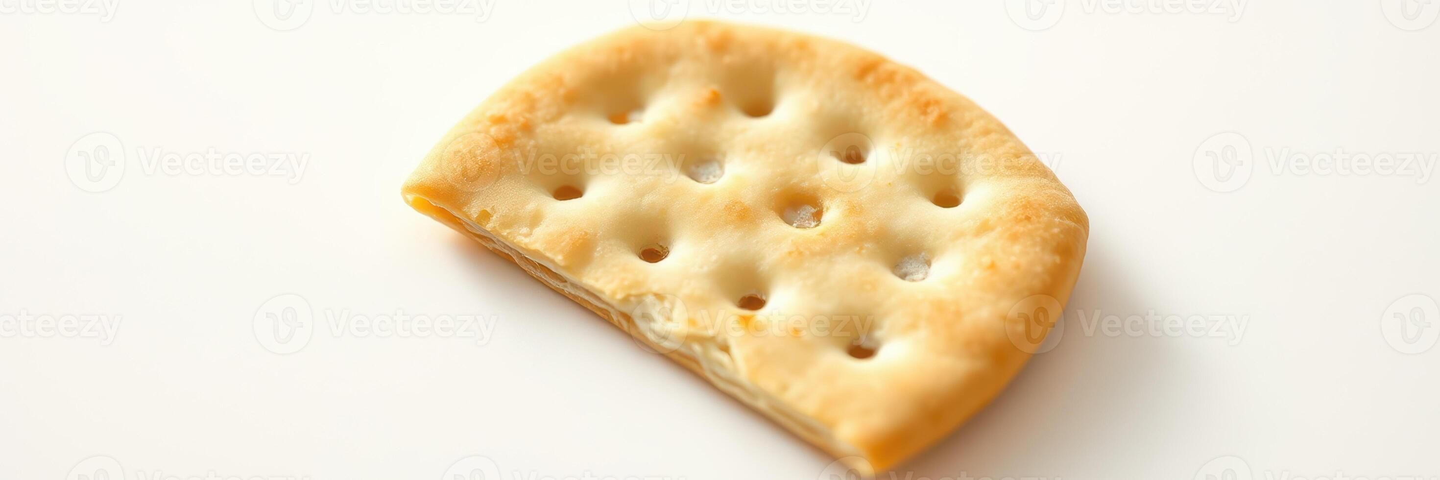 Cracker with holes rests on a plain background, showcasing its texture and shape in a simple still life photo