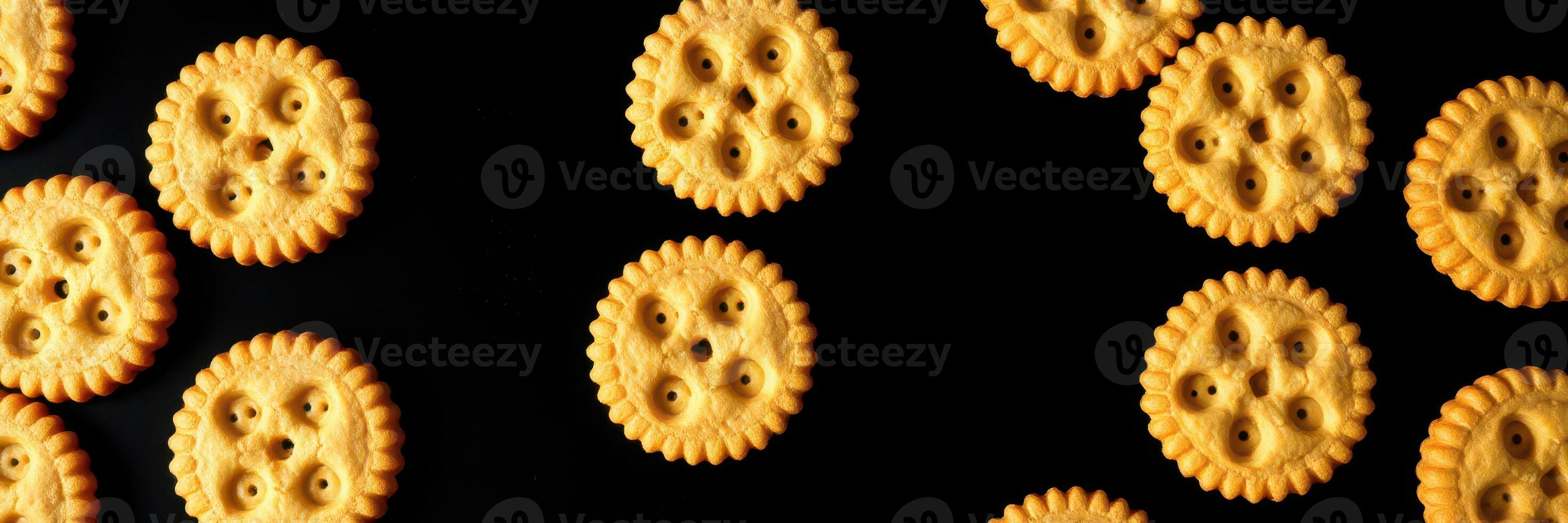 Colorful round crackers arranged in a playful pattern on a black background during a bright day photo
