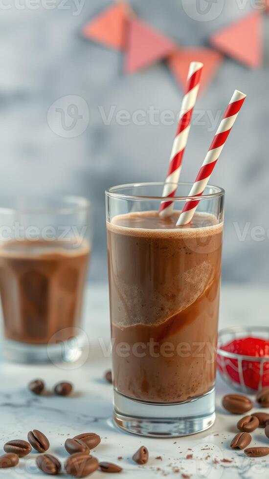 Refreshing chocolate beverage served in a glass with striped straws beside a plate of coffee beans at a festive gathering photo