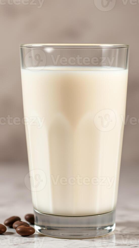 Fresh milk in a clear glass is beautifully displayed with coffee beans on a marble surface photo