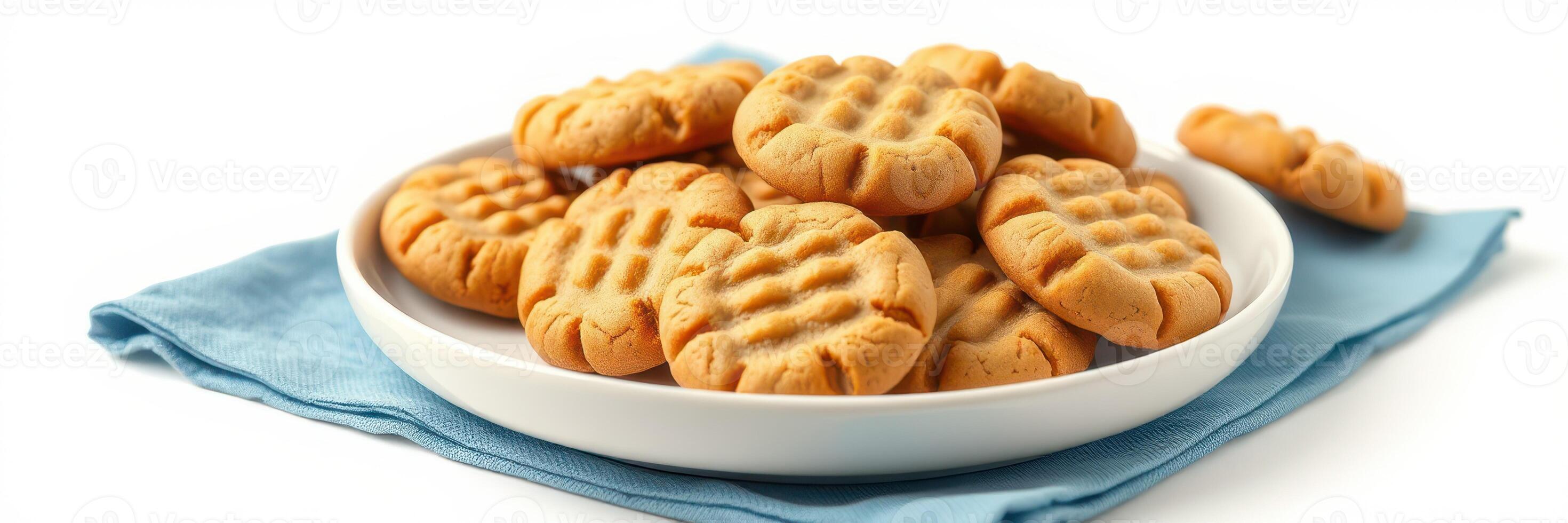Freshly baked peanut butter cookies arranged neatly on a white plate with a blue cloth underneath photo