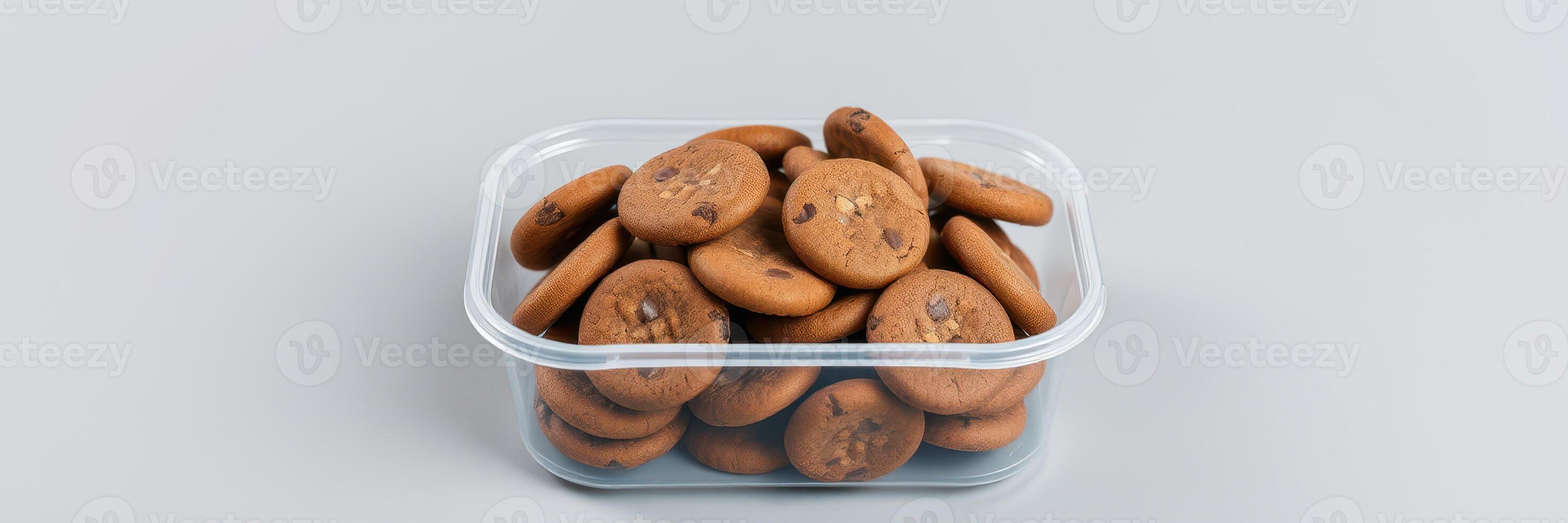 Freshly baked chocolate chip cookies displayed in a clear container on a neutral surface photo