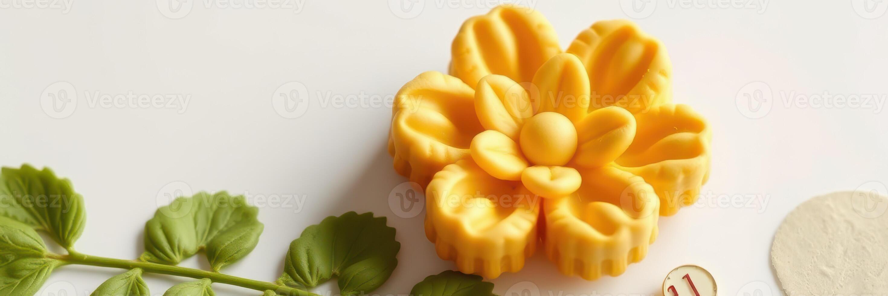 Decorative yellow flower shaped butter rests on a white surface beside green leaves and a round disk at a kitchen workspace photo