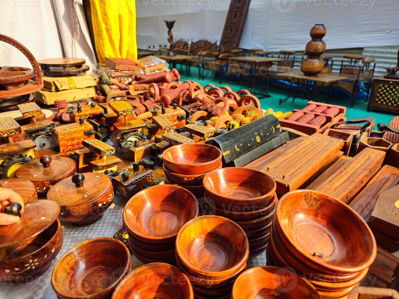 a variety of polished wooden bowls, trays, coasters, and other handcrafted items. The intricate patterns carved into the wood highlight the skill of the artisans. photo
